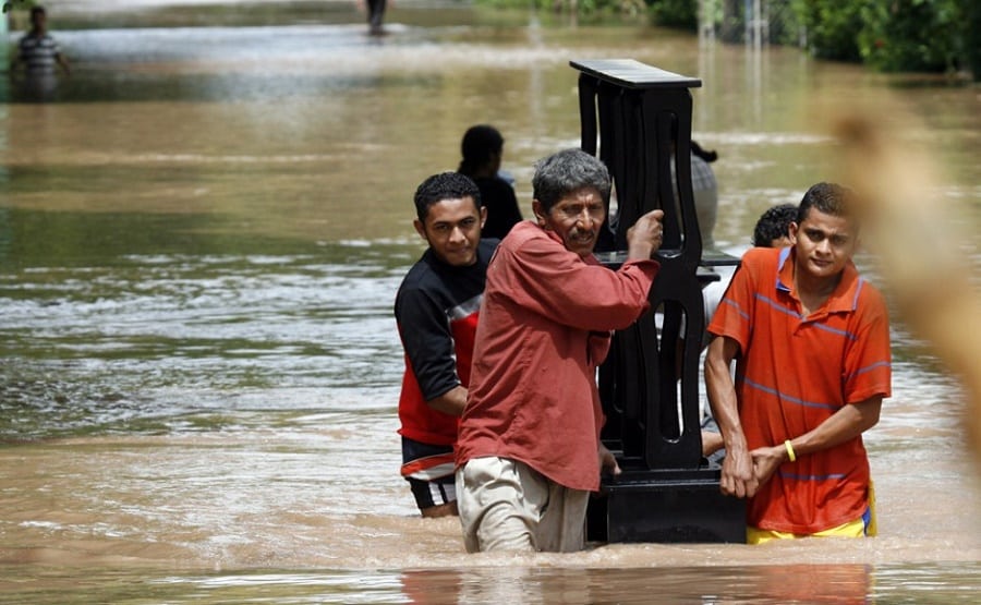 Residents struggle with their belongings through a flooded street in Hunduras |Photo credit: latincorrespondent.com